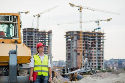 Responsable de chantier portant un casque rouge et un gilet de sécurité sur un chantier de construction urbain